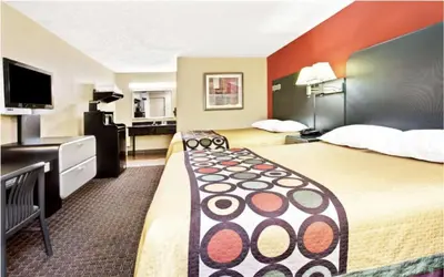 a hotel room with two beds and a flat screen tv at Super 8 by Wyndham Kissimmee/Maingate/Orlando Area in Orlando