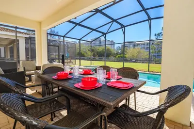 a wooden table and chairs on a patio with a pool at Flagstone Villa in Orlando