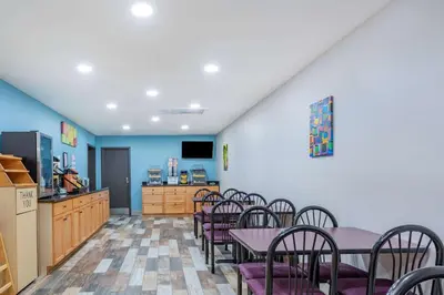 a dining room with tables and chairs and a kitchen at Days Inn by Wyndham N Orlando/Casselberry in Orlando
