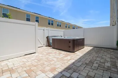 a backyard with a white fence and a wooden table at 4Bd Sleeps 9 w Jacuzzi Close to Disney @ Compass Bay 5113C in Kissimmee