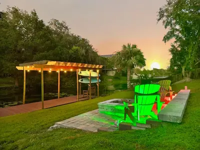 a backyard with a gazebo and green chairs at Lakefront 7 Bedroom Duplex, Pool, Boat, and Hottub in Orlando