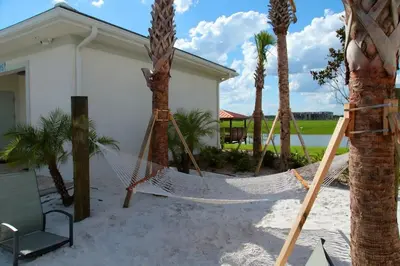 a hammock in front of a house with palm trees at Five Bedrooms Single Family 4759 in Kissimmee