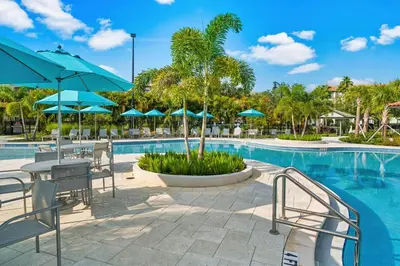 a pool with tables and chairs and blue umbrellas at Shoreway Loop Unit 206 Condo in Orlando
