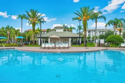 a swimming pool in front of a house with palm trees at Cayview Avenue Unit 404 Condo in Orlando