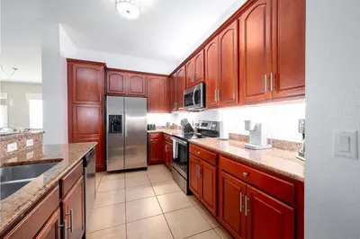 a kitchen with wooden cabinets and a stainless steel refrigerator at Shoreway Loop Unit 407 Condo in Orlando
