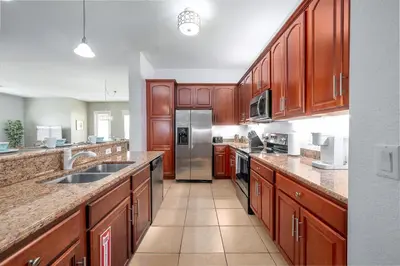 a kitchen with wooden cabinets and a stainless steel refrigerator at Shoreway Loop Unit 407 Condo in Orlando
