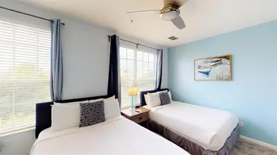 two beds in a room with blue walls and windows at Lovely Townhome at Vista Cay Resort near WDW in Orlando
