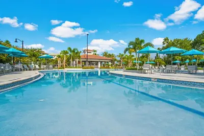 a swimming pool at a resort with blue umbrellas at Beautiful Condo w Private Balcony Near Universal in Orlando