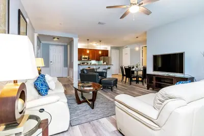 a living room with white furniture and a flat screen tv at Beautiful Condo w Private Balcony Near Universal in Orlando