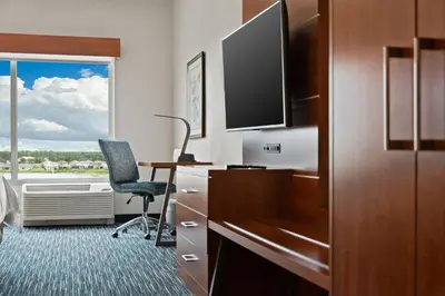 a hotel room with a desk and a chair and a window at Holiday Inn Express & Suites Orlando- Lake Buena Vista by IHG in Orlando