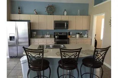 a kitchen with a counter with chairs and a refrigerator at Holiday Villas of Kissimmee in Kissimmee