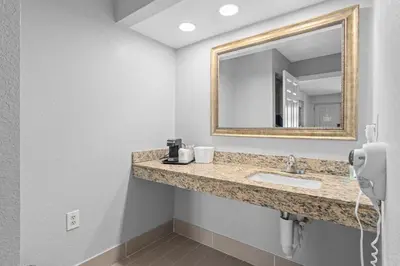 a bathroom with a sink and a mirror at Baymont by Wyndham Orlando East in Orlando