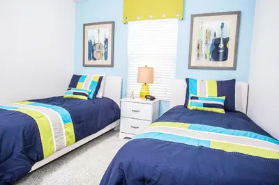 two beds in a bedroom with blue and yellow at Four Bedroom Close to Disney 5149A in Kissimmee
