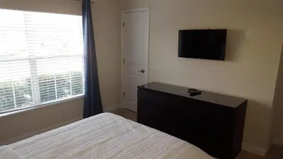 a bedroom with a bed and a tv on the wall at 4 Bedroom Private Lakefront Town Home at Storey Lake near Disney World Parks in Kissimmee