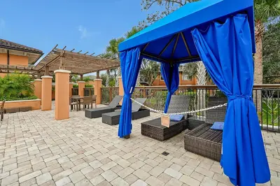 a gazebo with blue curtains on a patio at Regal Oaks Resort Vacation Townhomes by IDILIQ in Orlando