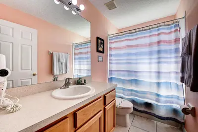 a bathroom with a sink and a toilet and a mirror at Margaritavilla at Emerald Island in Kissimmee