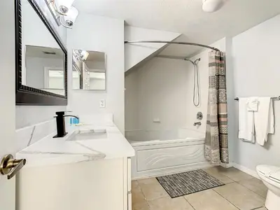 a white bathroom with a sink and a bath tub at 4 Bedroom Townhouse in a Gated Resort! in Kissimmee
