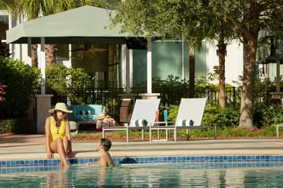 a woman and a boy sitting in a swimming pool at Hilton Orlando in Orlando