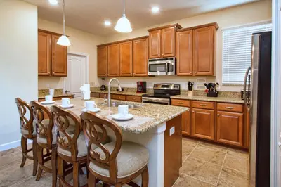 a kitchen with wooden cabinets and a kitchen island with chairs at Very Private Pool & Spa, Spacious, Wifi - 3507Pp in Kissimmee
