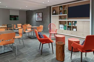 a dining room with tables and chairs and a flat screen tv at Home2 Suites By Hilton Orlando Near Universal in Orlando