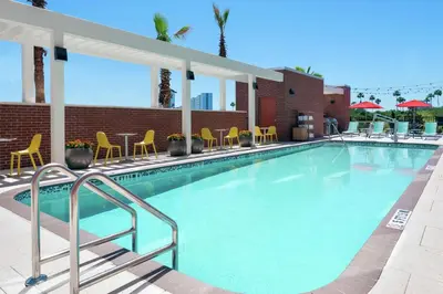 a large swimming pool with yellow chairs and tables at Home2 Suites By Hilton Orlando Near Universal in Orlando