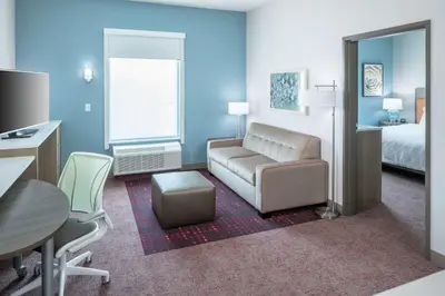 a hotel room with a couch and a bed at Home2 Suites By Hilton Orlando Airport in Orlando
