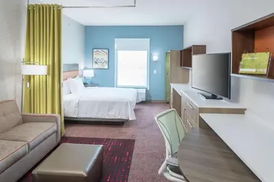 a hotel room with a bed and a couch at Home2 Suites By Hilton Orlando Airport in Orlando