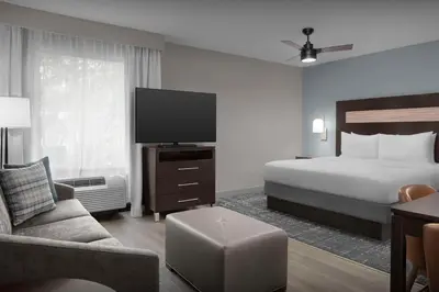 a hotel room with a bed and a flat screen tv at Homewood Suites by Hilton Orlando Airport in Orlando
