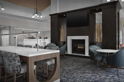 a lobby with a fireplace and chairs and a table at Homewood Suites by Hilton Orlando Airport in Orlando