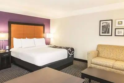 a hotel room with a bed and a chair at La Quinta by Wyndham Orlando Airport - On Property Food Trucks & Free Airport Shuttle! in Orlando