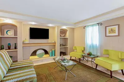 a living room with a couch and chairs and a tv at La Quinta Inn by Wyndham Orlando Airport West in Orlando