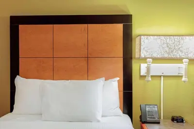 a hotel room with a bed with a phone next to it at La Quinta Inn by Wyndham Orlando Airport West in Orlando
