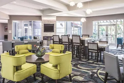 a lobby with a waiting room with tables and chairs at La Quinta by Wyndham Orlando Lake Mary in Lake Mary