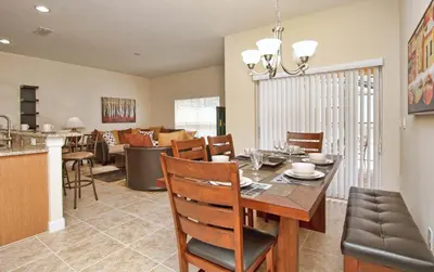 a dining room and living room with a table and chairs at South Facing Pool Wsplashpool- 3080Pp in Kissimmee