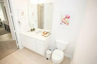 a white bathroom with a toilet and a sink at Modern Vacation Apartment with a Lake View in Orlando
