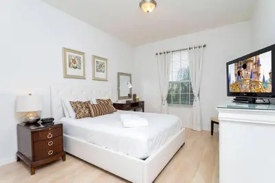 a white bedroom with a bed and a flat screen tv at Gorgeous Apartment in Orlando at Vista Cay Resort in Orlando