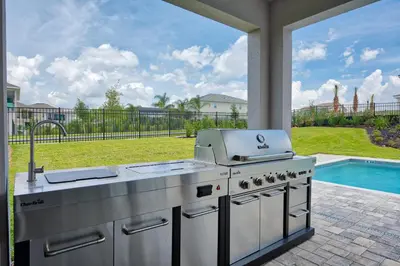 a barbecue grill on a patio with a pool at Gorgeous Home With Private Pool, Themed Rooms Near Disney With Waterpark & Resort Access At Encore Resort - 7687Ff in Kissimmee