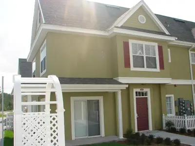 a yellow house with a white ladder in front of it at Venetian Bay Villa 4 Bedroom Townhouse - Near Disney in Kissimmee