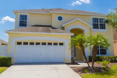 a house with a garage and a palm tree at Disney Dream with Hot Tub, Pool, Xbox, Games Room, Lakeview, 10 min to Disney, Clubhouse in Kissimmee