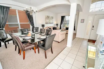 a dining room and living room with a table and chairs at Disney Dream with Hot Tub, Pool, Xbox, Games Room, Lakeview, 10 min to Disney, Clubhouse in Kissimmee