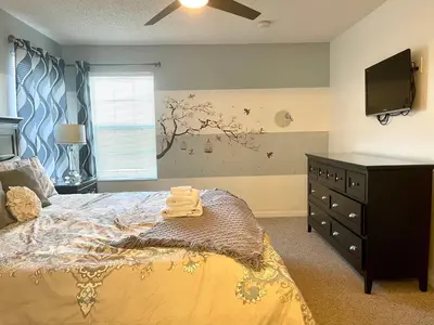 a bedroom with a bed with a dresser and a tv at Disney Dream with Hot Tub, Pool, Xbox, Games Room, Lakeview, 10 min to Disney, Clubhouse in Kissimmee
