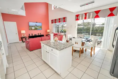 a kitchen and living room with a red wall at Disney Dream with Hot Tub, Pool, Xbox, Games Room, Lakeview, 10 min to Disney, Clubhouse in Kissimmee