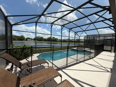 a glass pavilion with a swimming pool and benches at Seasons Villa 6 bedrooms, 4 masters and water view in Kissimmee