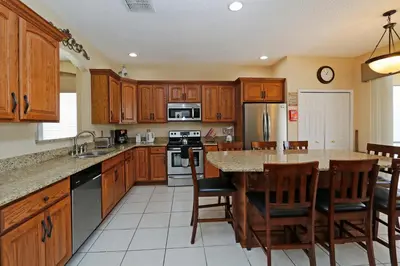 a kitchen with wooden cabinets and a large island with a table at The Villa at Terra Verde in Kissimmee