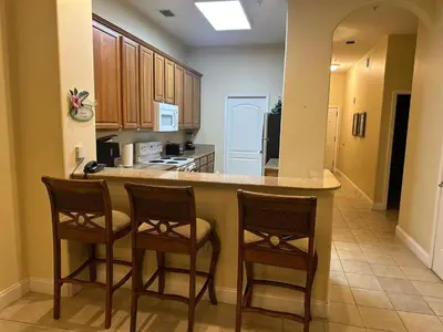 a kitchen with two bar stools and a counter at Penthouse Close to Disney area and Malls water view in Orlando