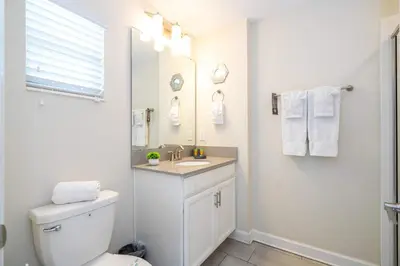 a white bathroom with a toilet and a sink at Stunning 5 Bd Home w/ Pool Close to Disney 4822 in Kissimmee