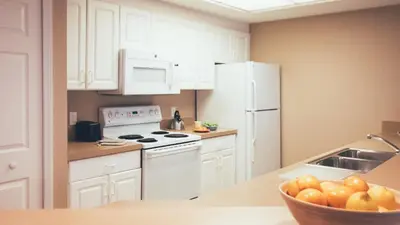 a kitchen with white cabinets and a bowl of fruit on a counter at Holiday Inn Club Vacations At Orange Lake Resort in Orlando
