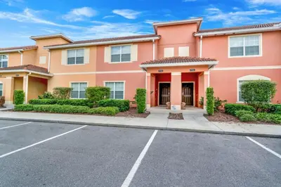 a large pink house with a parking lot at Cuban Palm Townhouse #275805 Townhouse in Kissimmee