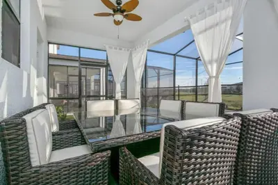 a patio with wicker chairs and a glass table at 2901FS - Amazing 8 bedroom at Storey Lake in Kissimmee