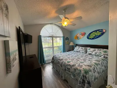 a bedroom with a bed with a ceiling fan and a window at House By the Mouse in Kissimmee